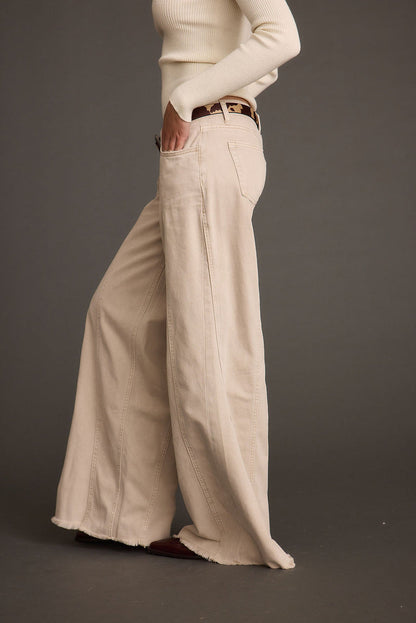 Lifestyle shot of the beige jeans styled for day-to-night versatility.